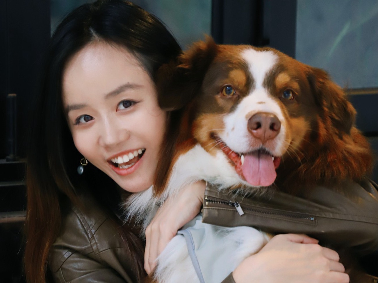 Emily smiling and hugging a large brown and white Australian Shepherd.